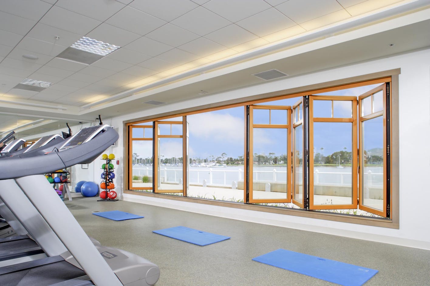 exercise room with wood framed folding glass wall open for fresh ar