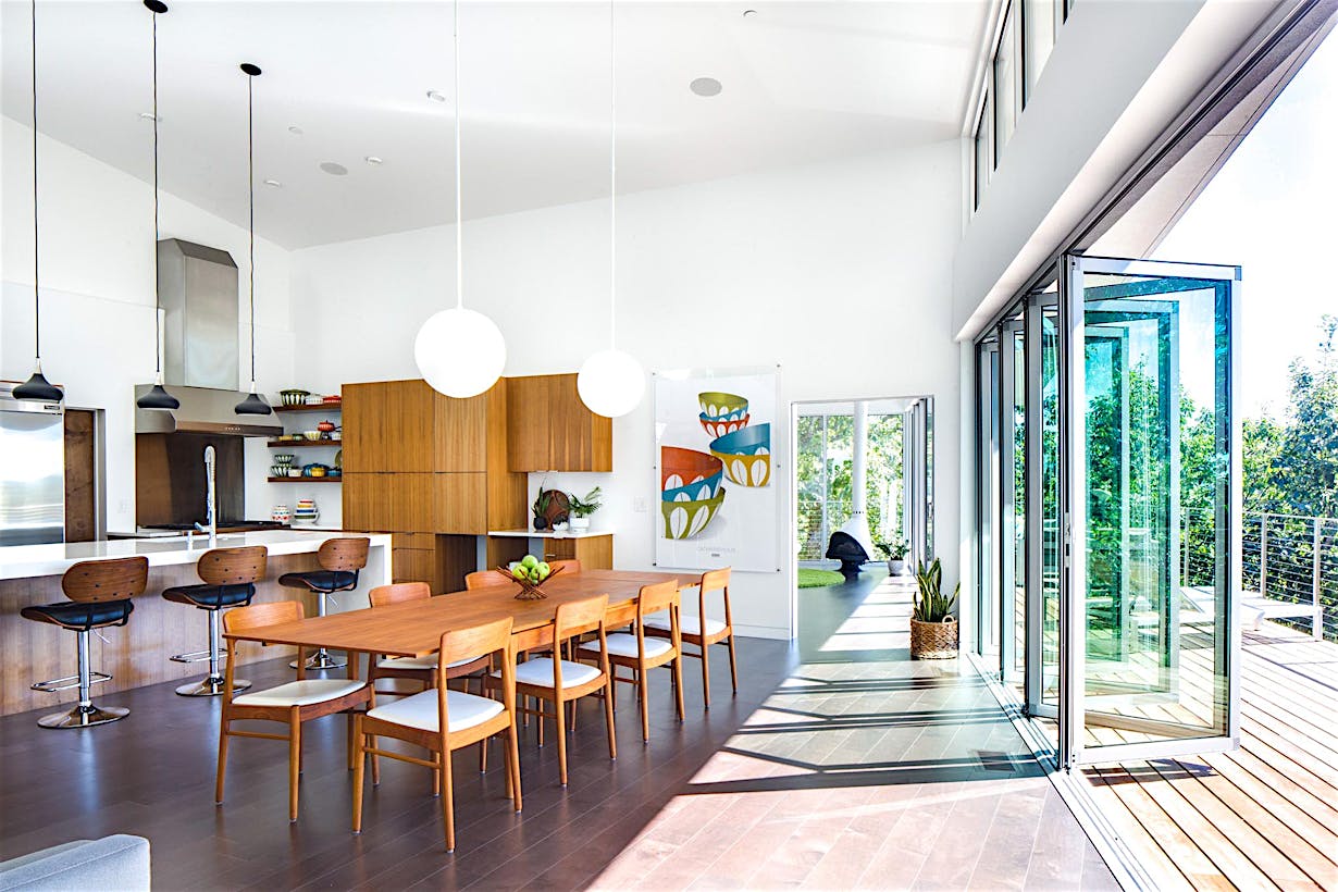 folding glass wall partially open in dining room with hillside view