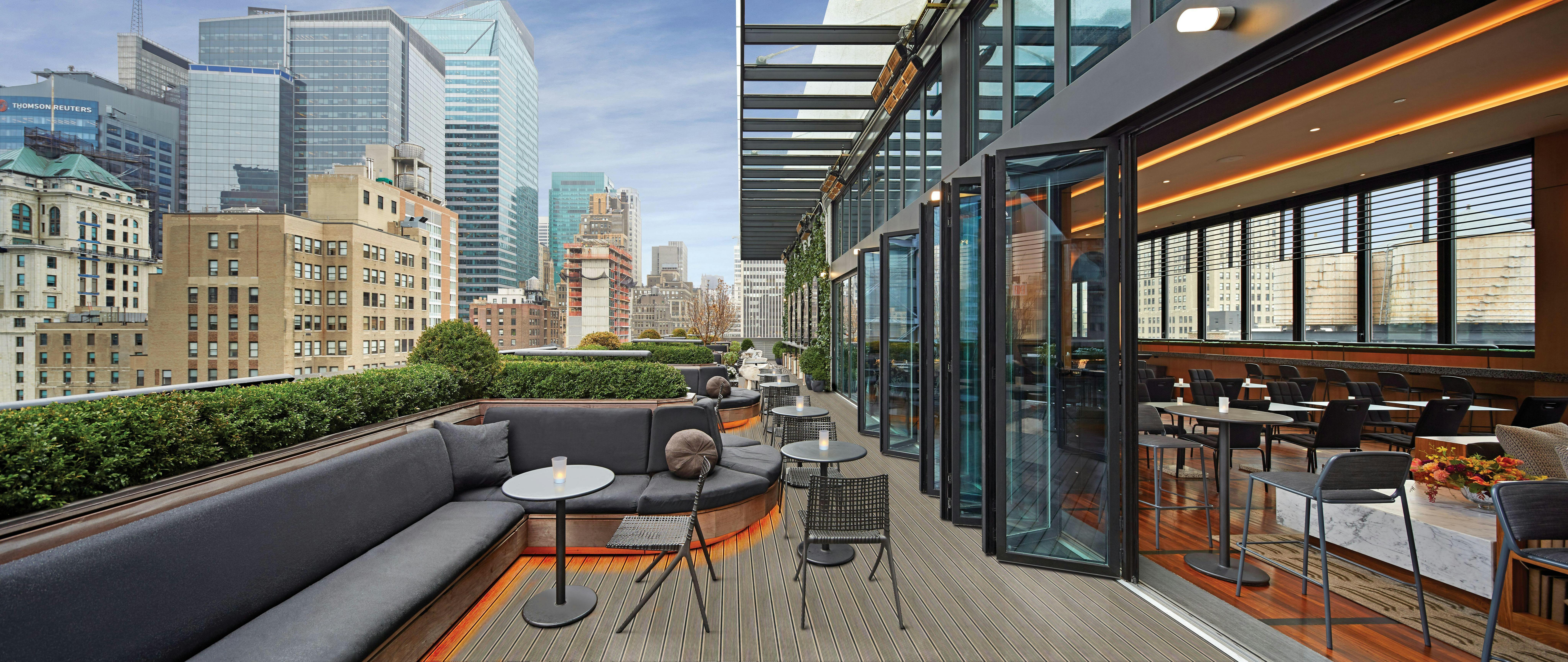 rooftop bar and restaurant in new york city with folding glass walls open to the balcony