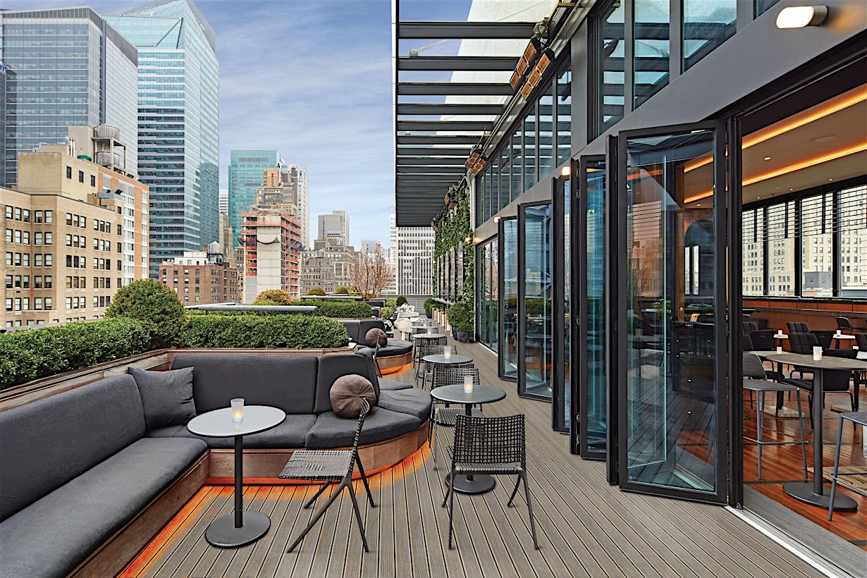rooftop bar and restaurant in new york city with folding glass walls open to the balcony