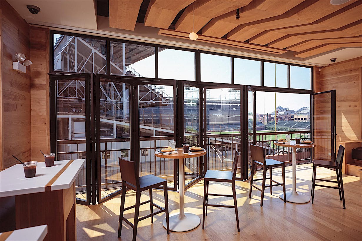 commercial folding glass wall system partially open with view of baseball view for live games