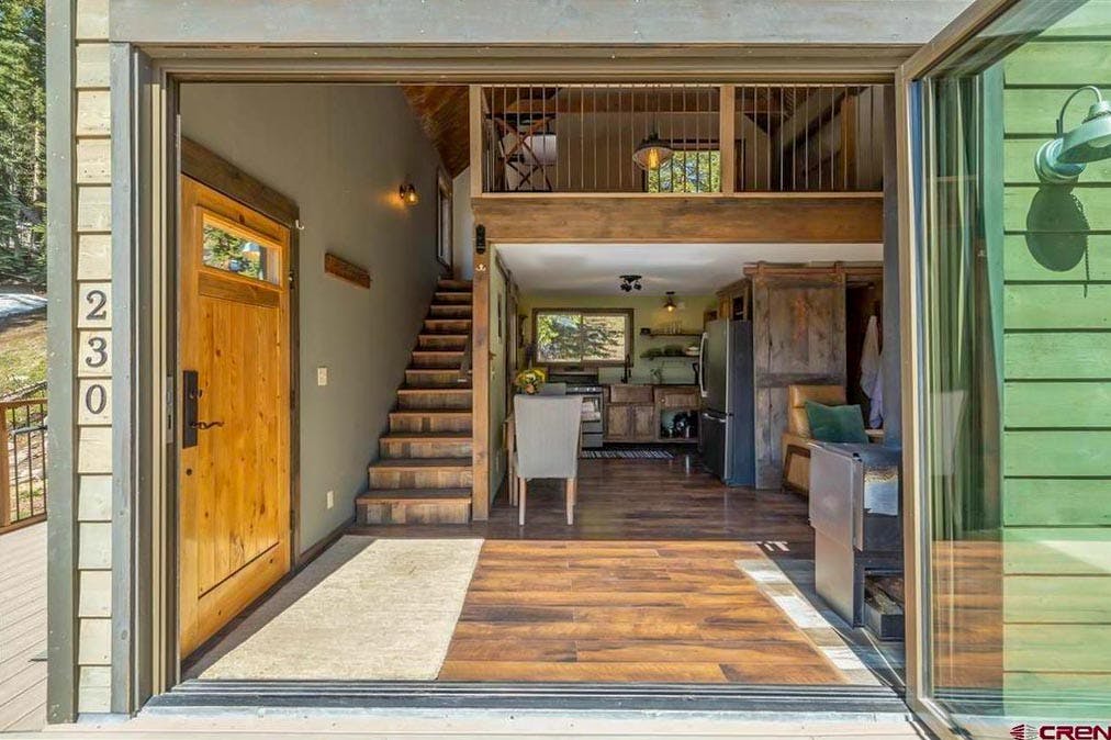 interior of tiny living home through open folding glass wall