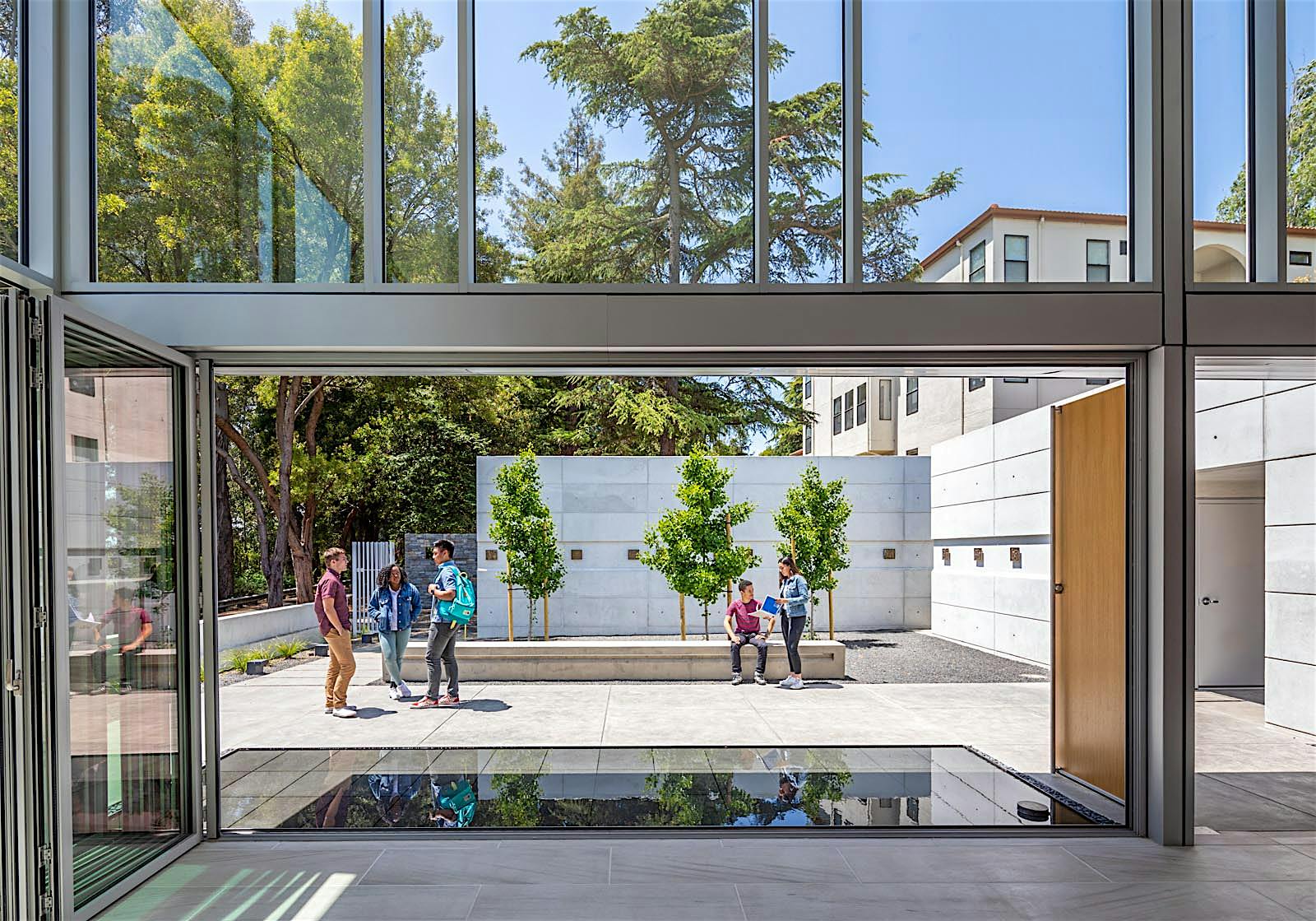 reflecting pond and courtyard through folding glass wall at saint mary's college high school