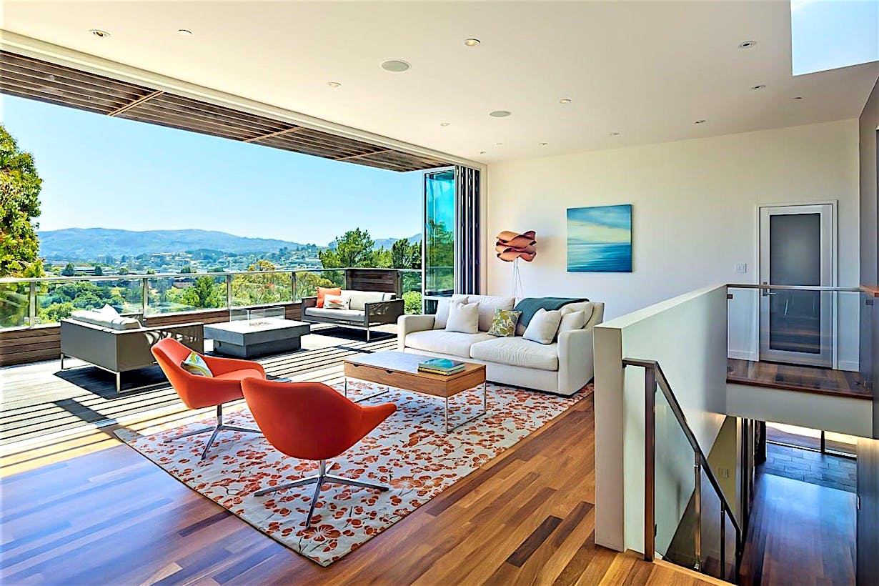 indoor/outdoor living achieved in hillside home with folding glass wall in living room remodel