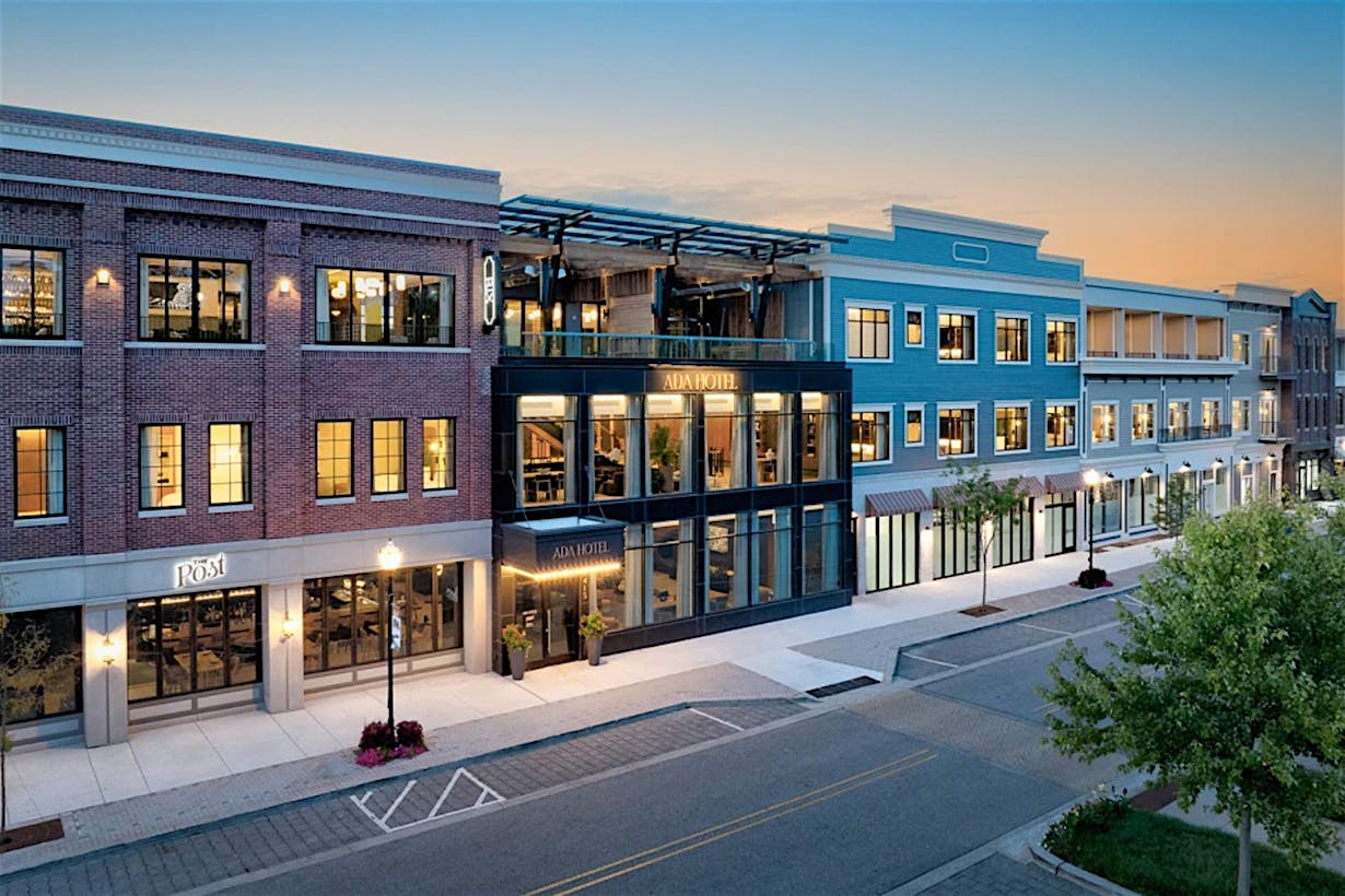 Street view of a mixed-use building merging historic and contemporary design elements. Building is featuring brick, blue facades, and large glass doors.