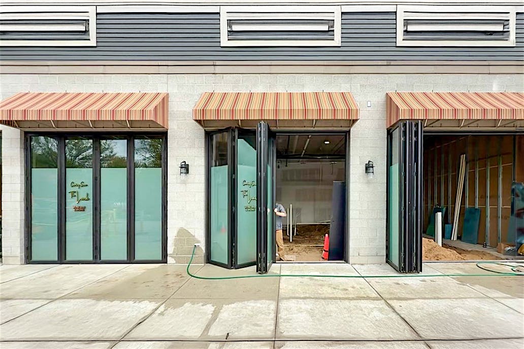 A building exterior features bifold glass doors, enhancing the hospitality design.