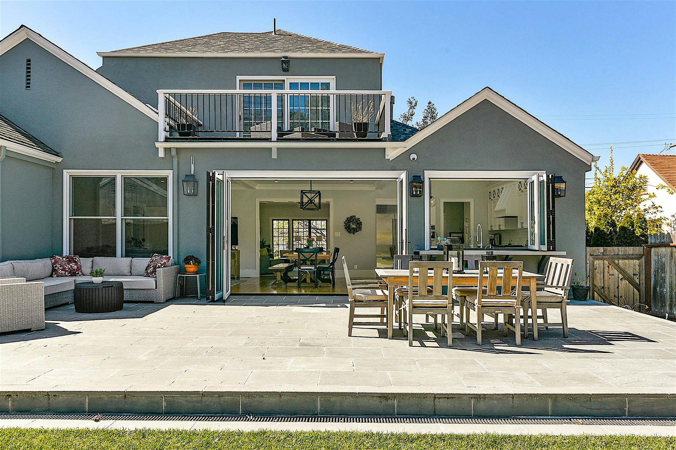 Modern backyard with patio furniture, dining set, and open folding doors leading to the interior showcases exquisite remodeling.