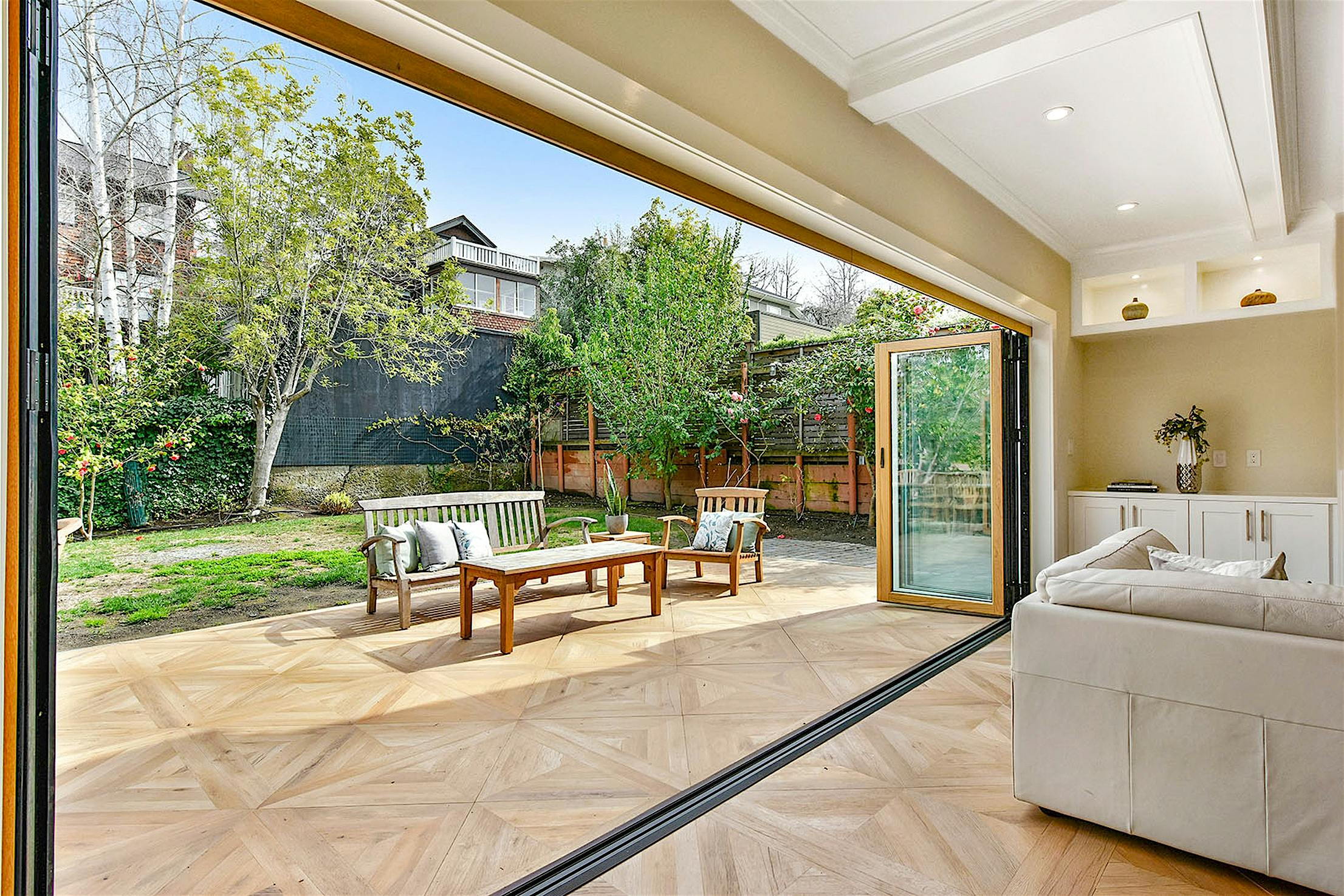 Spacious living area with sleek folding glass walls opening to a patio.