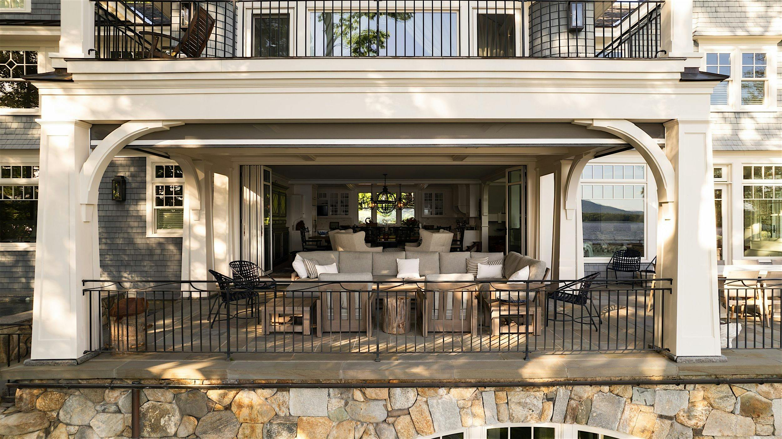 Spacious patio with a white frame and stone foundation, featuring outdoor furniture and white glass patio doors.