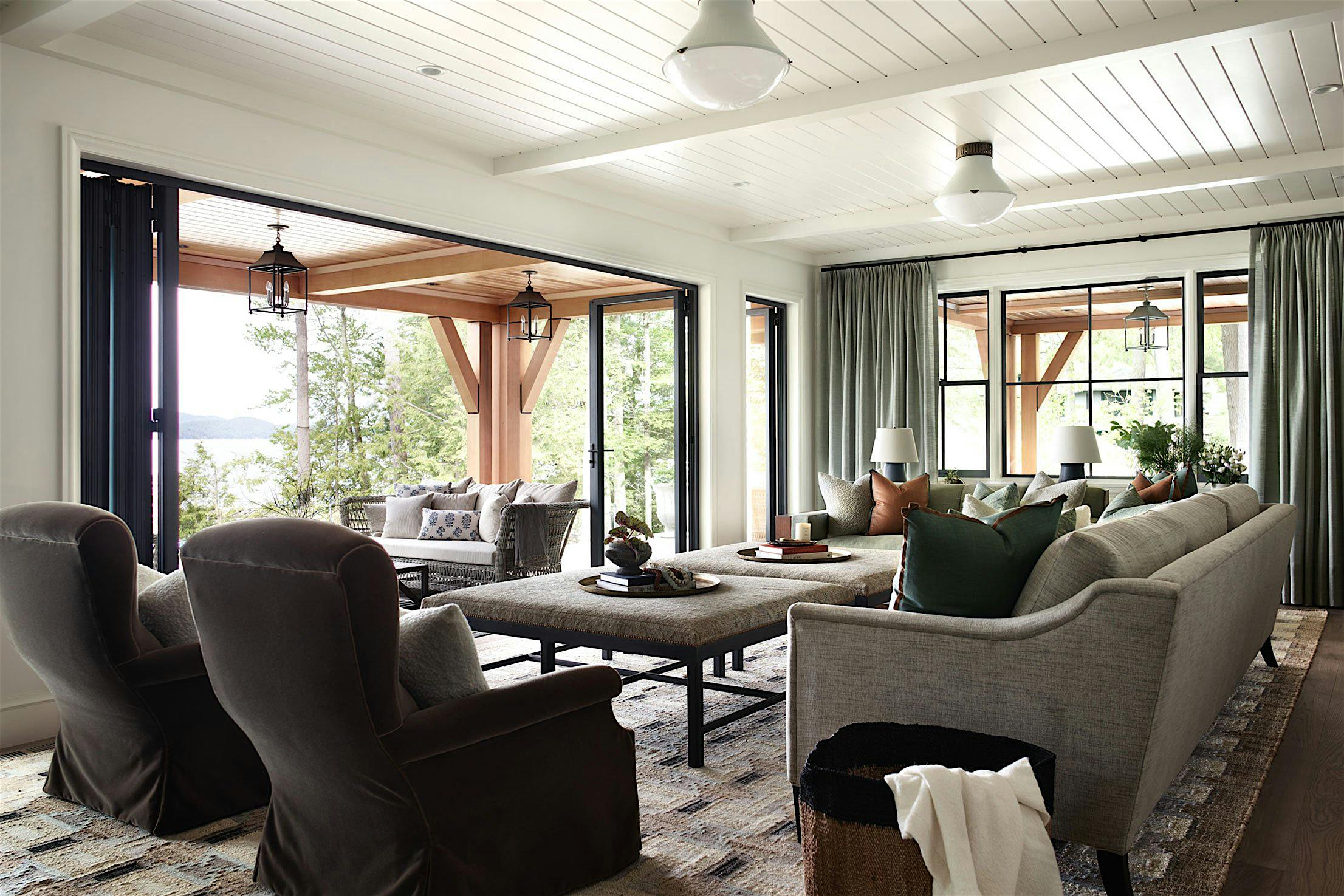 Spacious living room with folding patio doors that open to reveal a patio with seating and lush greenery outside.