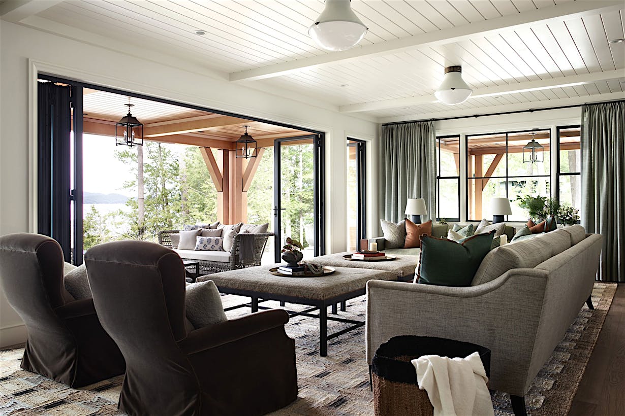 Spacious living room with folding patio doors that open to reveal a patio with seating and lush greenery outside.