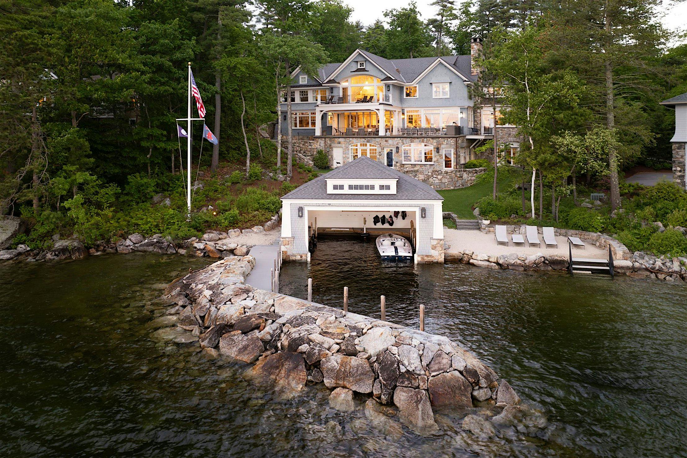 Large lakeside house with accordion patio doors, featuring a dock and boathouse.