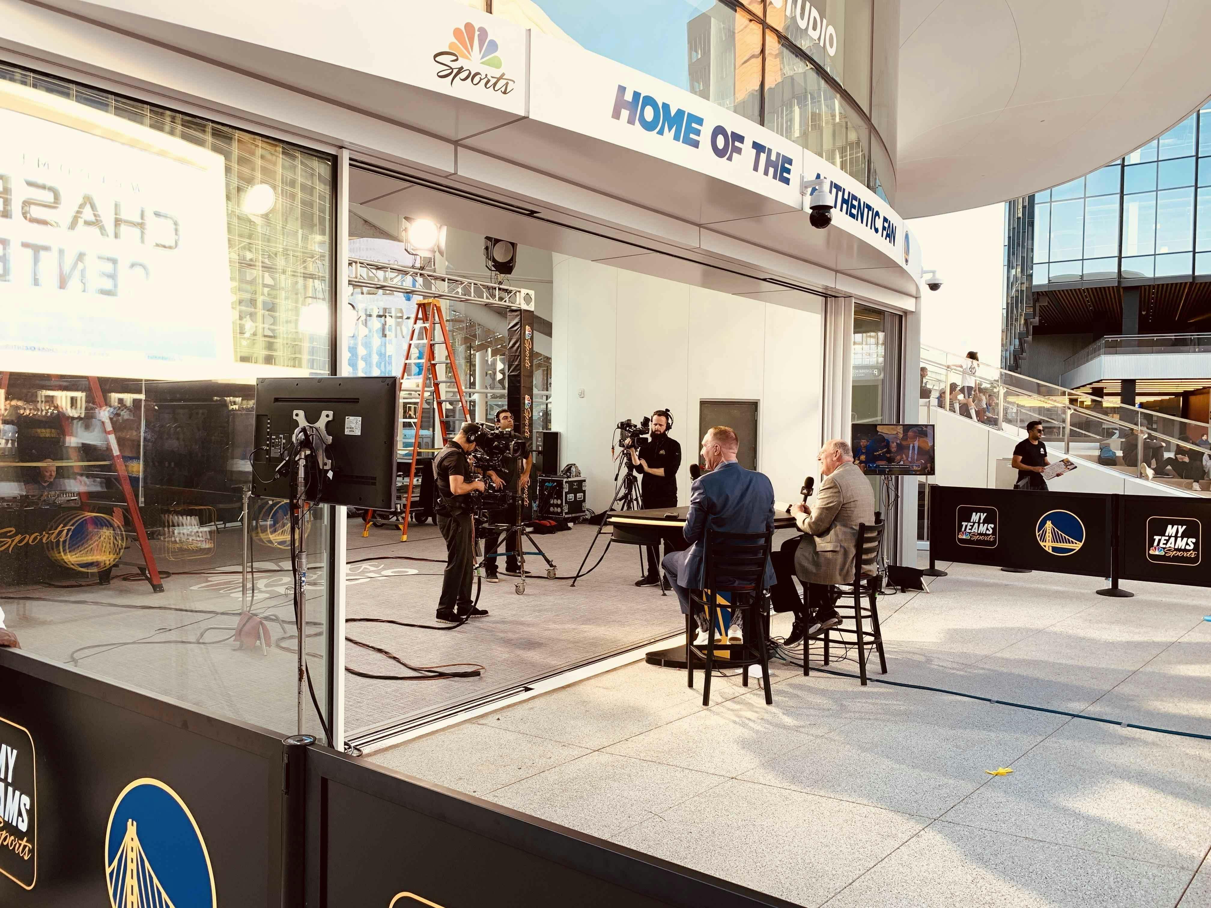 commentators-working-at-chase-center-near-sliding-glass-wall