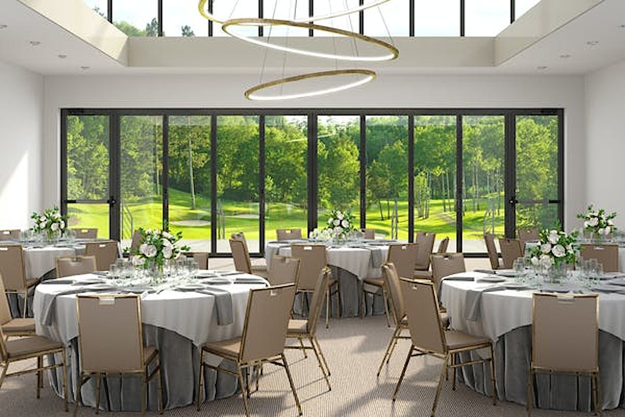 A banquet room with a view of a golf course, featuring commercial glass walls - closed doors