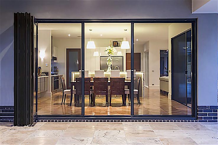 A modern dining room with large sliding glass doors, featuring fully retractable screening feature.