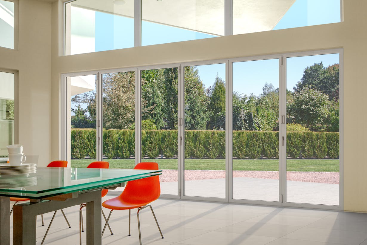 A sleek dining room with a slim aluminum framed glass walls - closed doors view