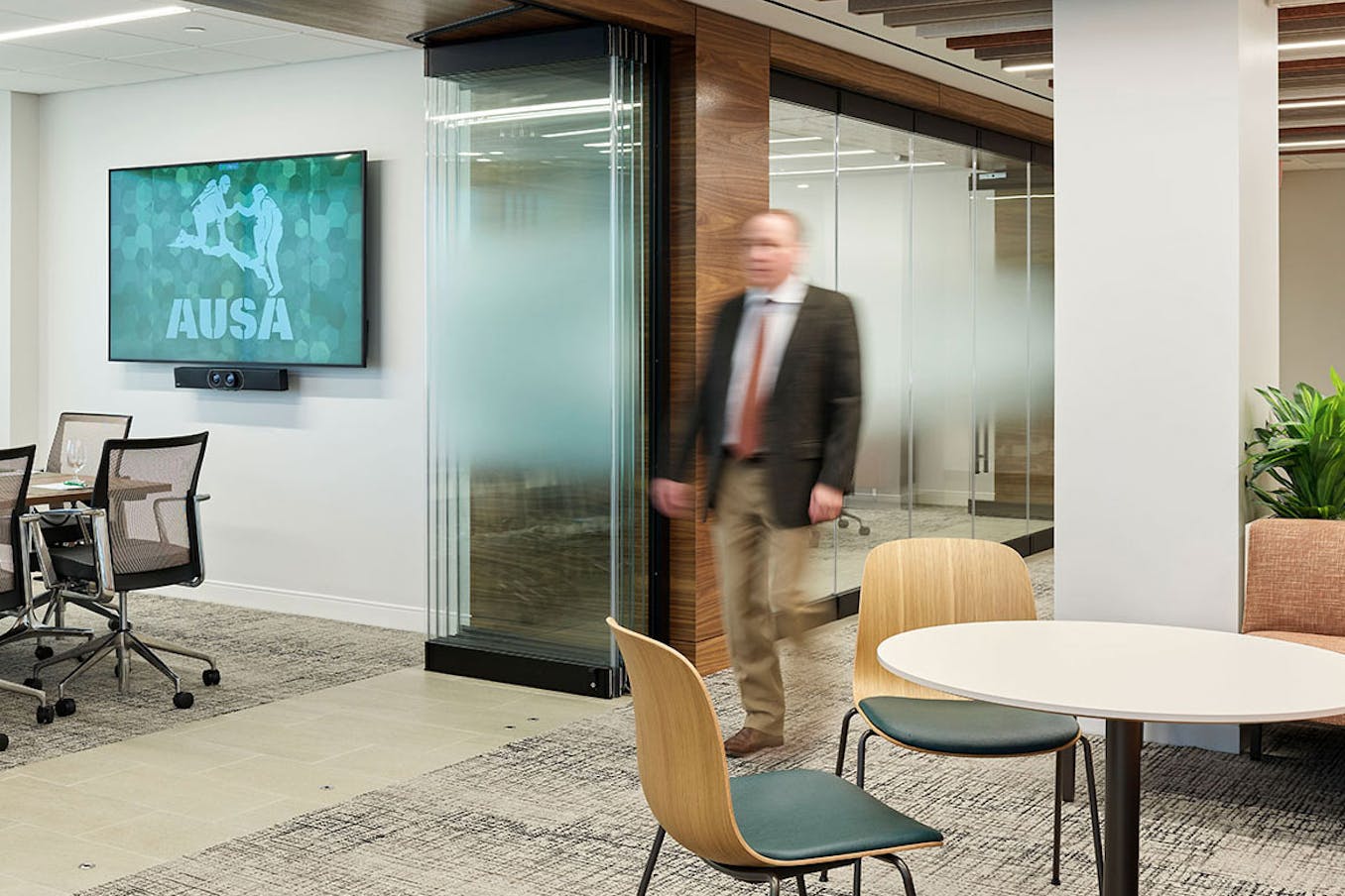 A man walks through an office conference room with frameless glass partitions