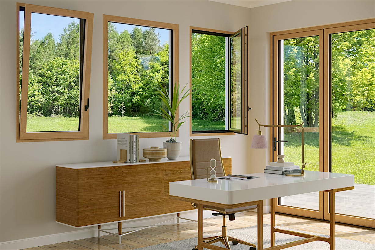 An office with a wooden table features Generation 4 folding glass walls and tilt turn windows, offering a uniform aesthetic and framing views of trees with yellow autumn leaves outside.