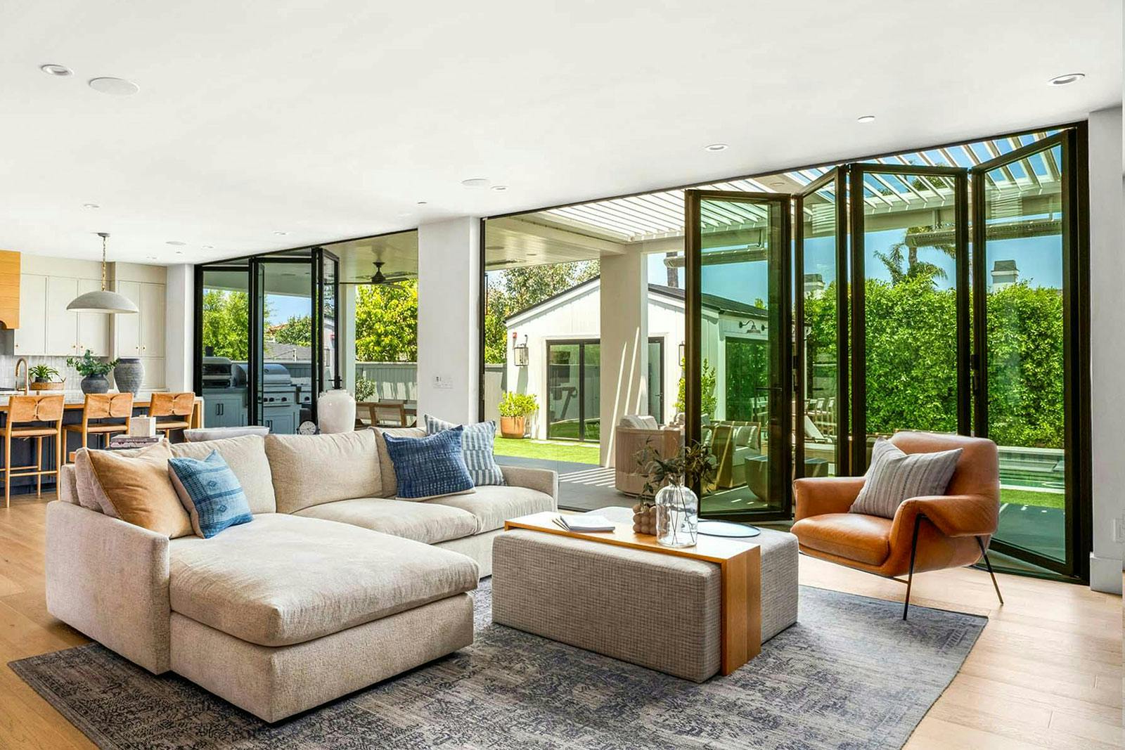NanaWall folding glass doors fully open, connecting a modern living room to an outdoor patio for seamless indoor outdoor living