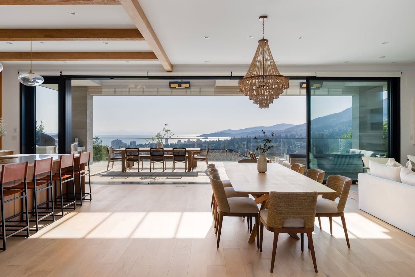 A modern kitchen and dining room with fully automated large opening glass walls, offering breathtaking views of the ocean