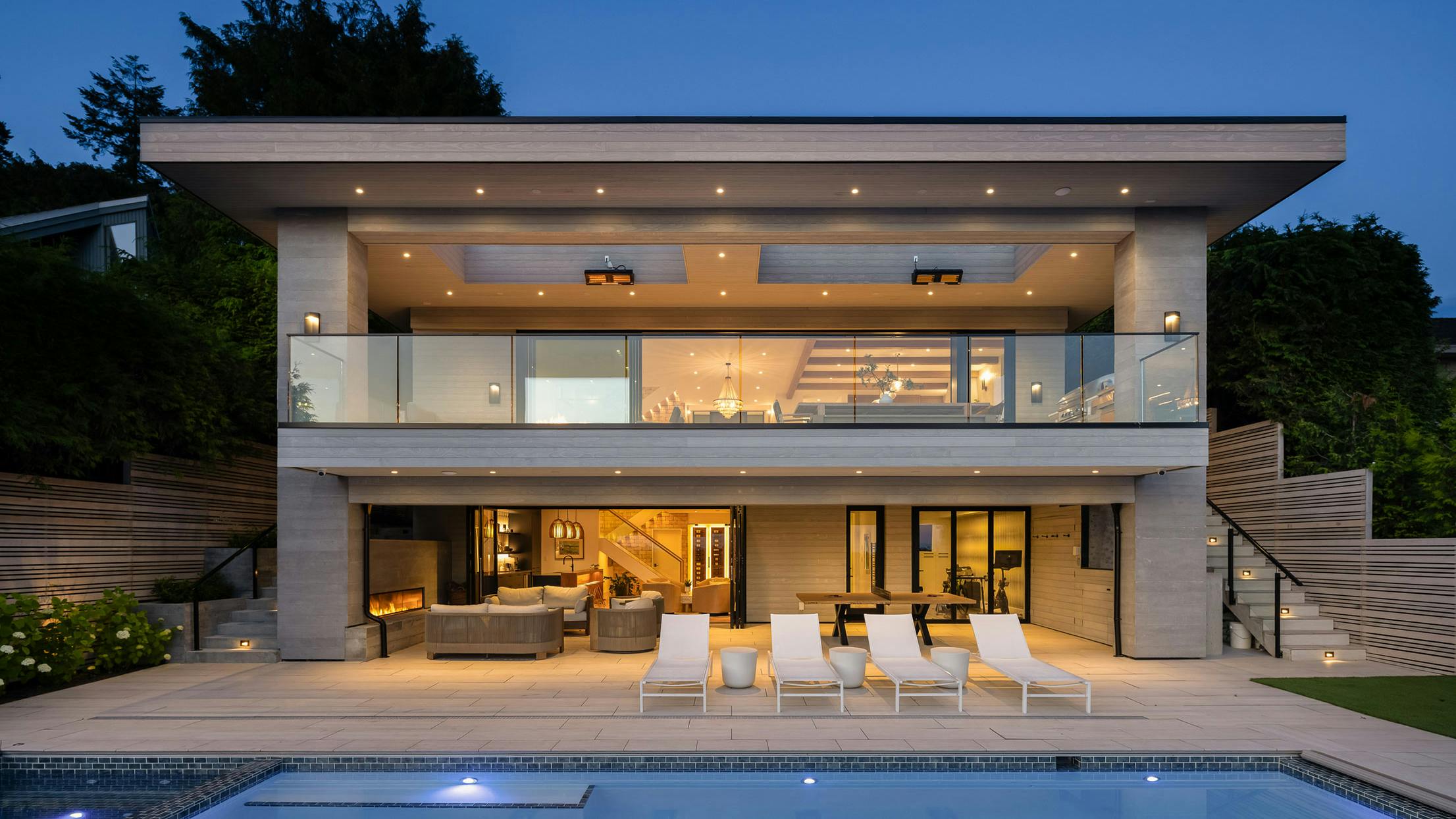 A modern house with minimal glass walls and a swimming pool at dusk