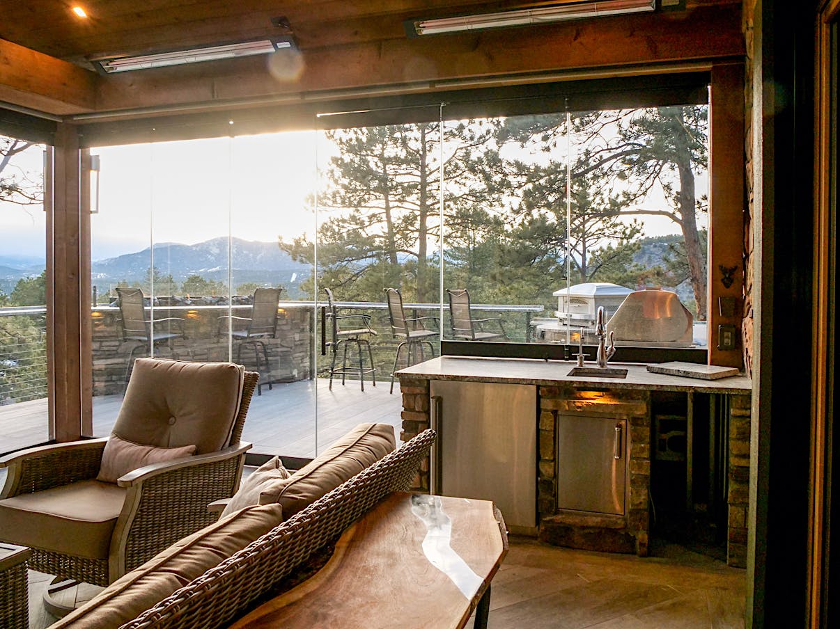 A living room with frameless glass walls showcasing a stunning view of the mountains