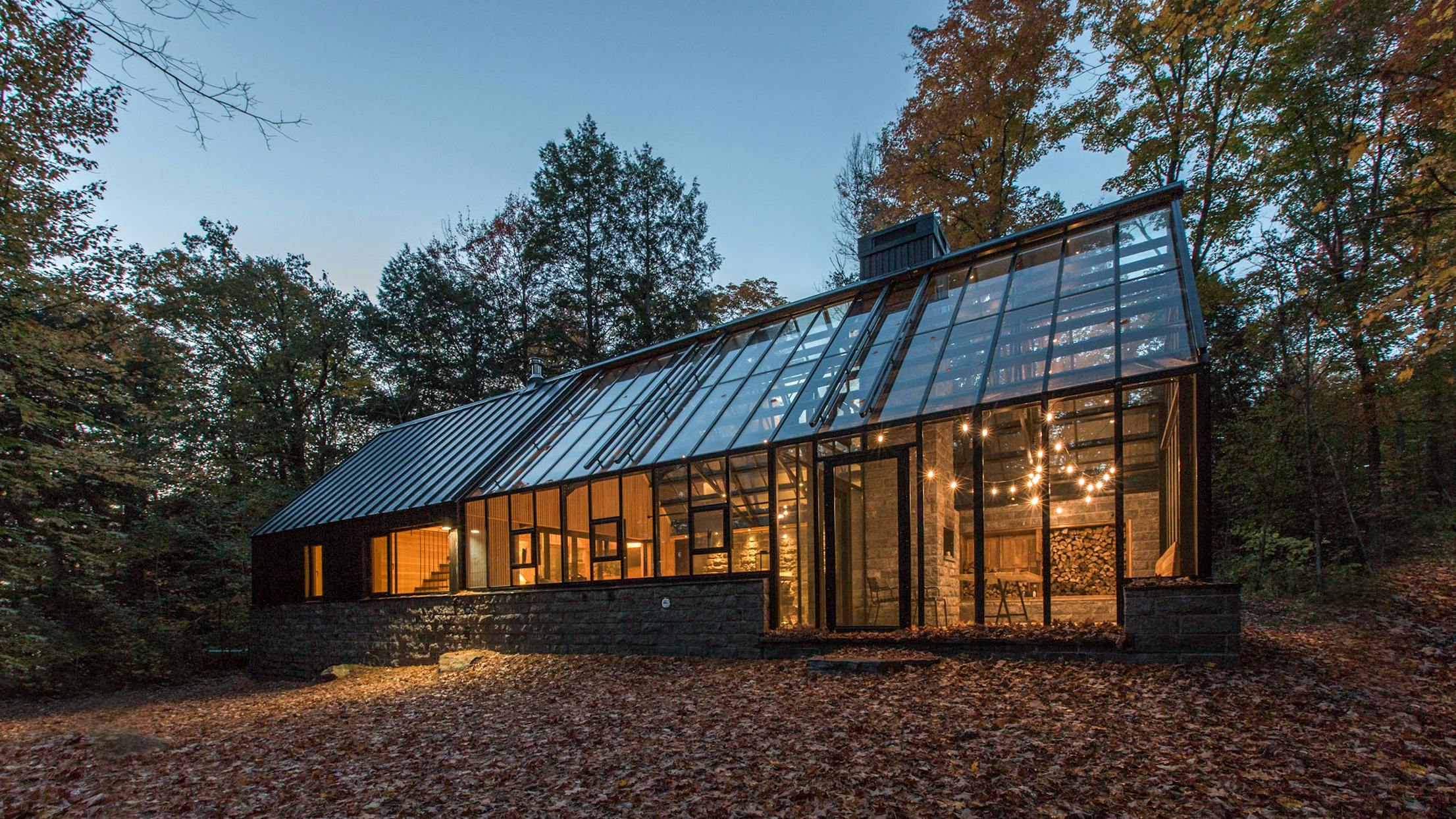 A modern glass house in the woods at dusk. A modern glass house in the woods at dusk