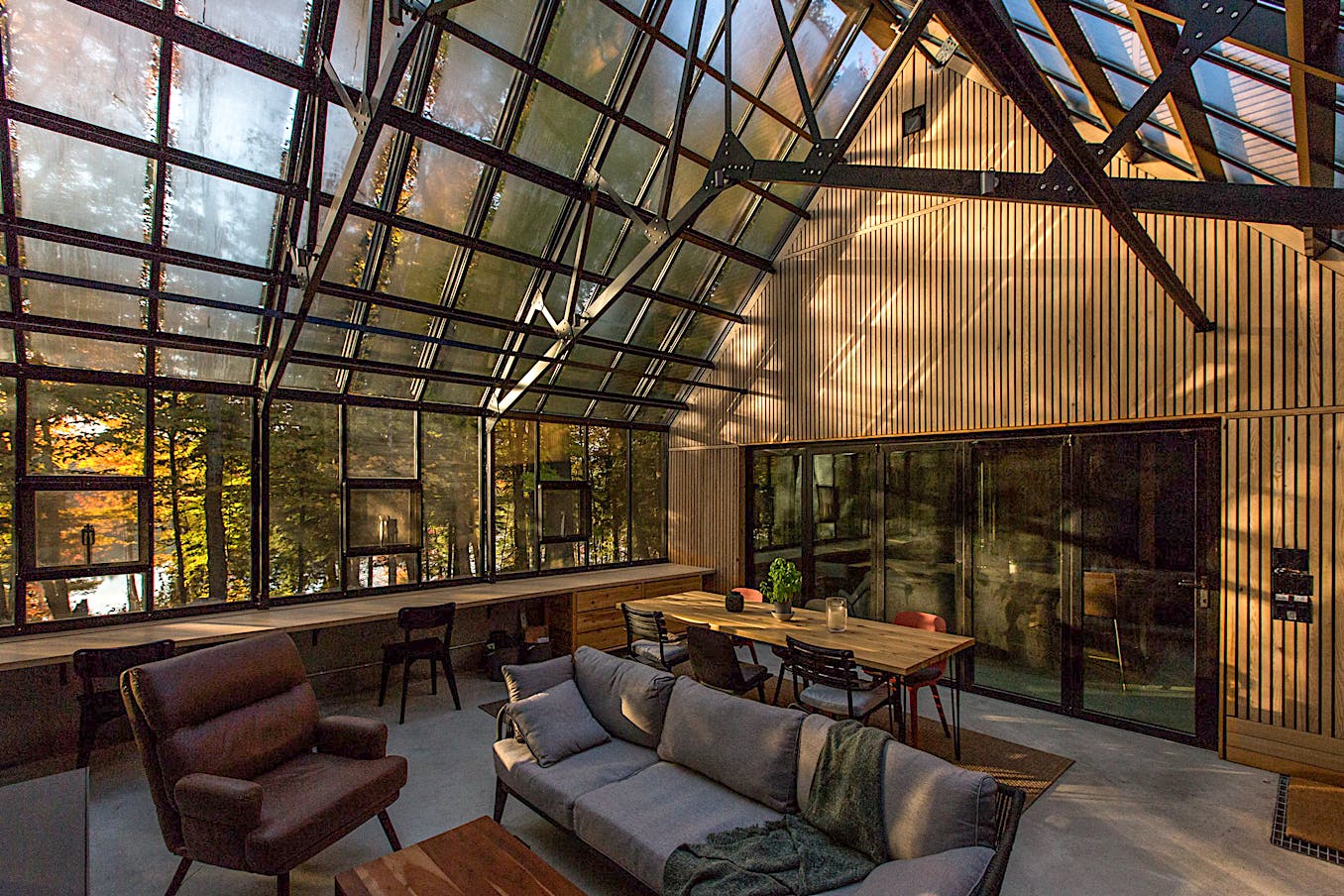 A greenhouse cottage with glass walls that offer a stunning view of the outdoors