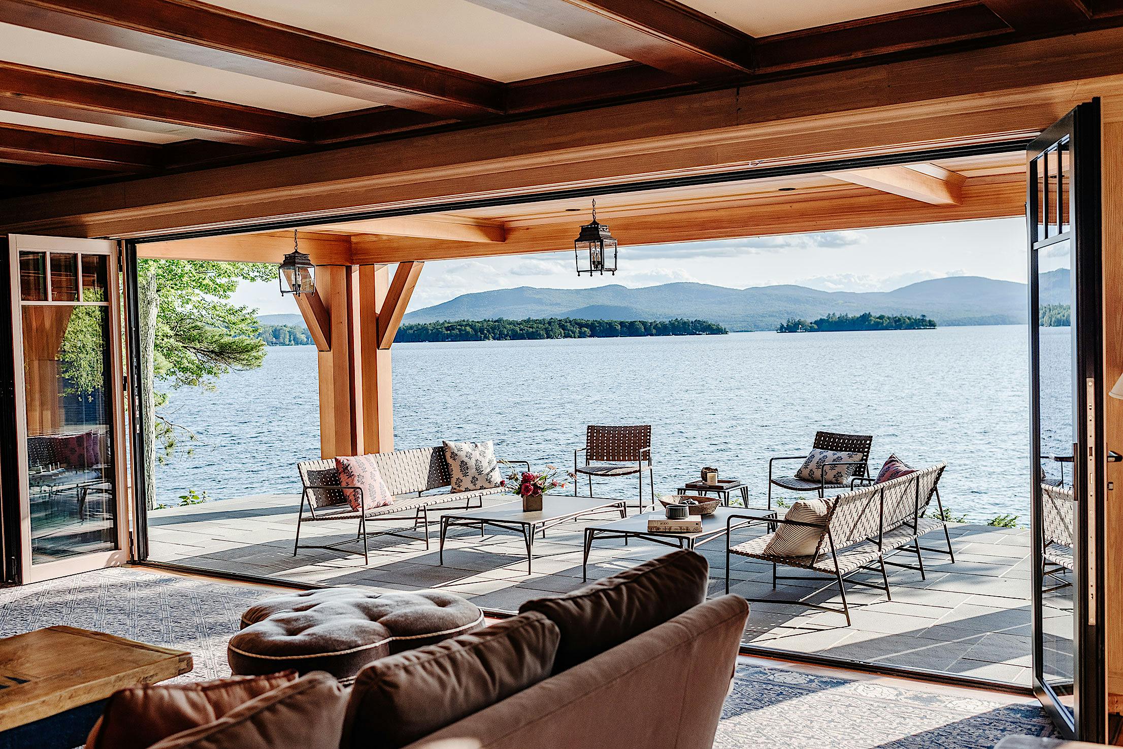 A spacious living room with folding glass walls that offer a stunning view of the serene lake