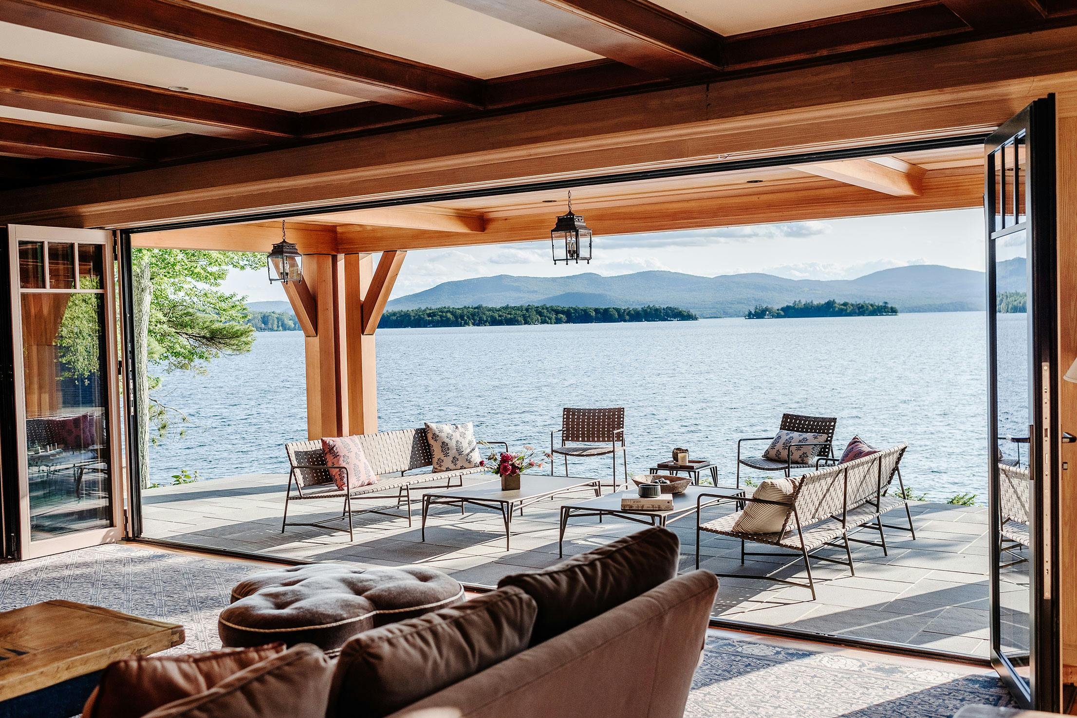 A spacious living room with folding glass walls that offer a stunning view of the serene lake
