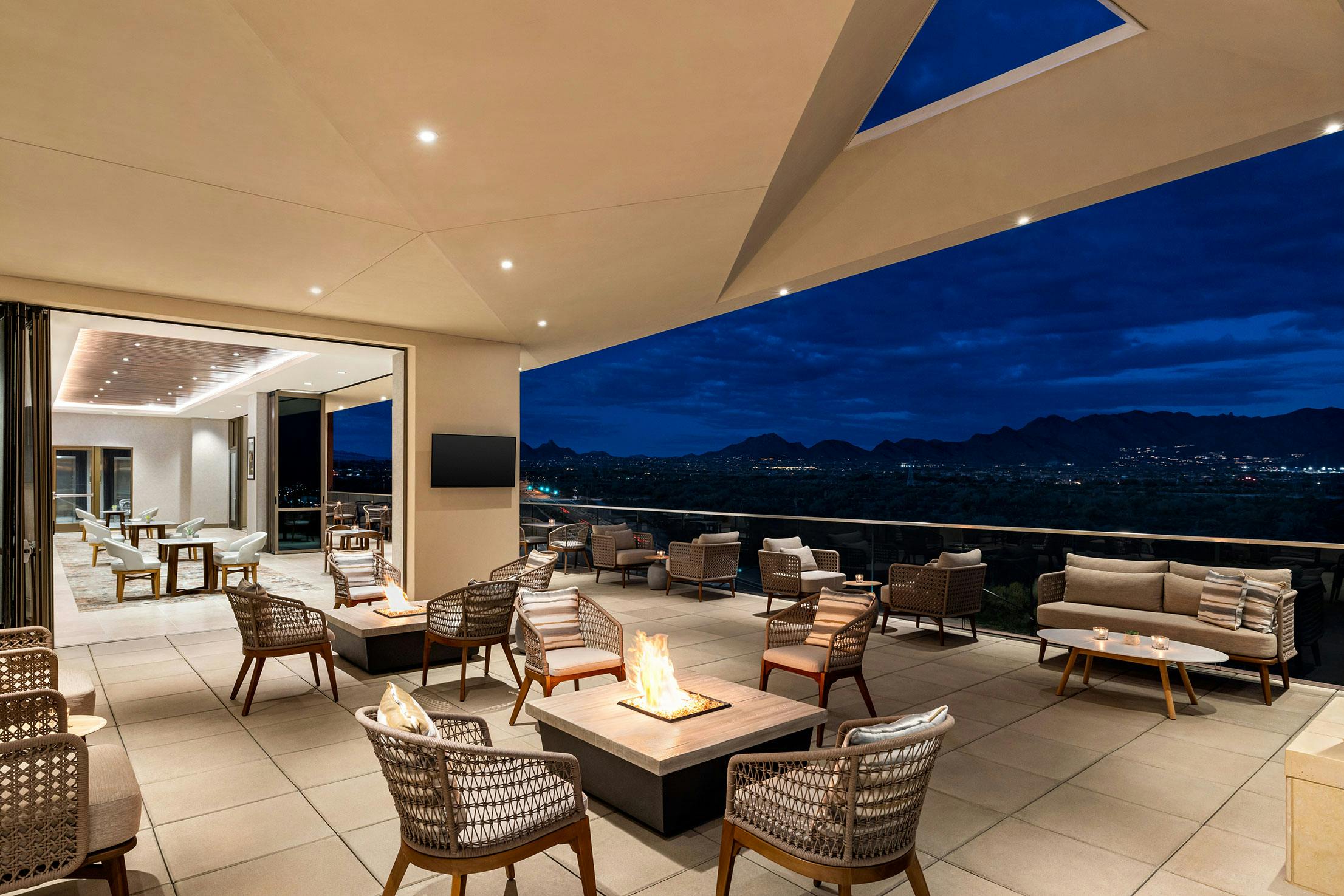 Hilton roof top lounge with a fire pit and a view of the mountains, enhanced by stunning commercial glass walls