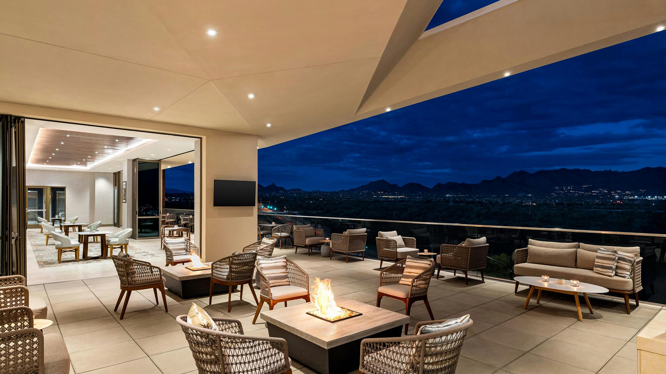 Hilton roof top lounge with a fire pit and a view of the mountains, enhanced by stunning commercial glass walls