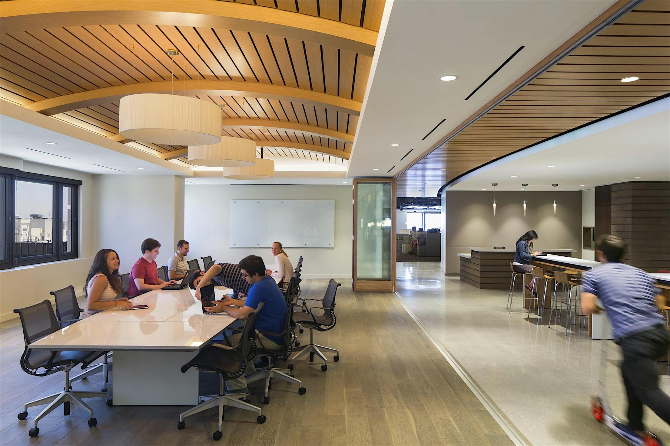 Office space with folding glass walls and a group of people sitting around a table