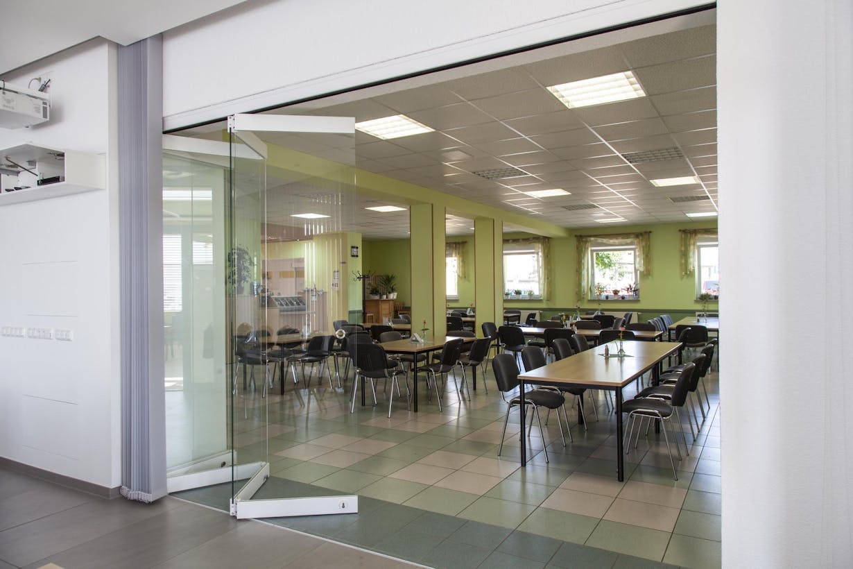 Frameless folding glass doors leading into a room with tables and chairs