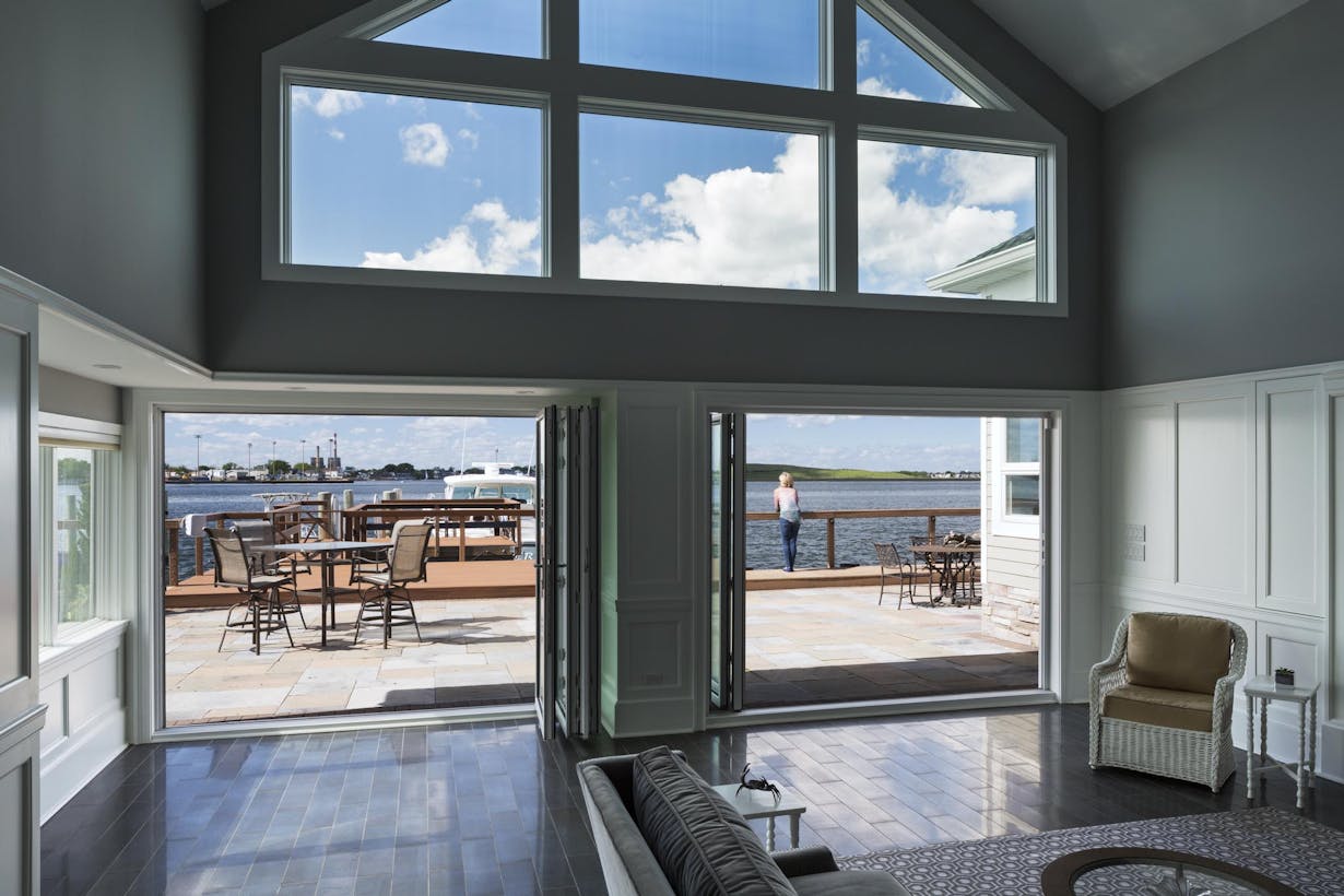A living room with large folding windows overlooking the water