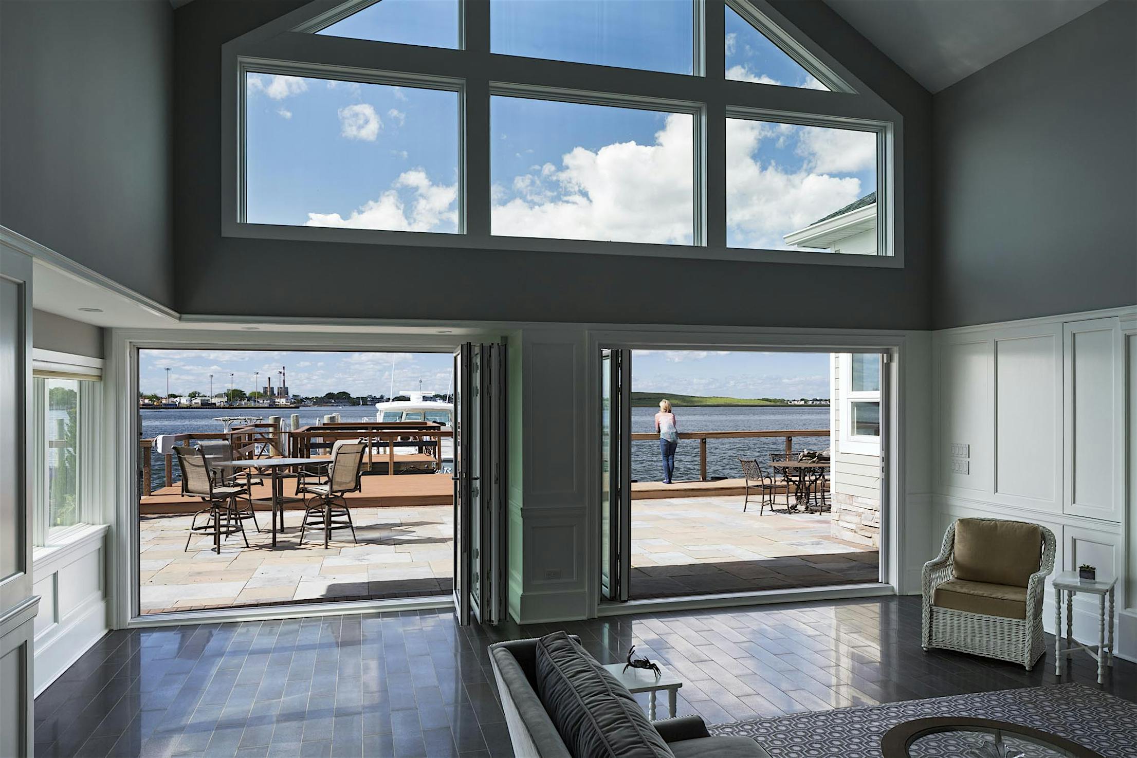 A living room with large folding windows overlooking the water