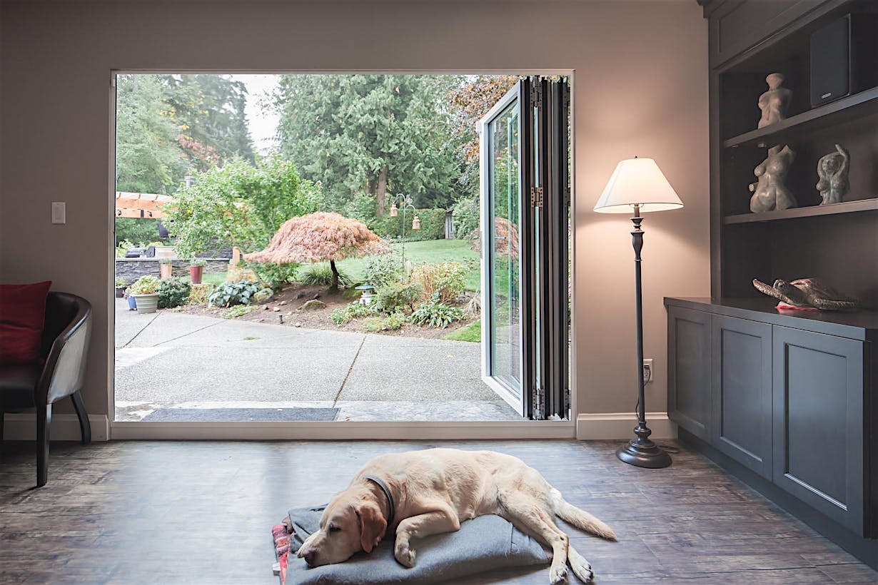 Retractable patio doors in South Surrey, BC fully open with panels stacked right, merging indoor and outdoor space