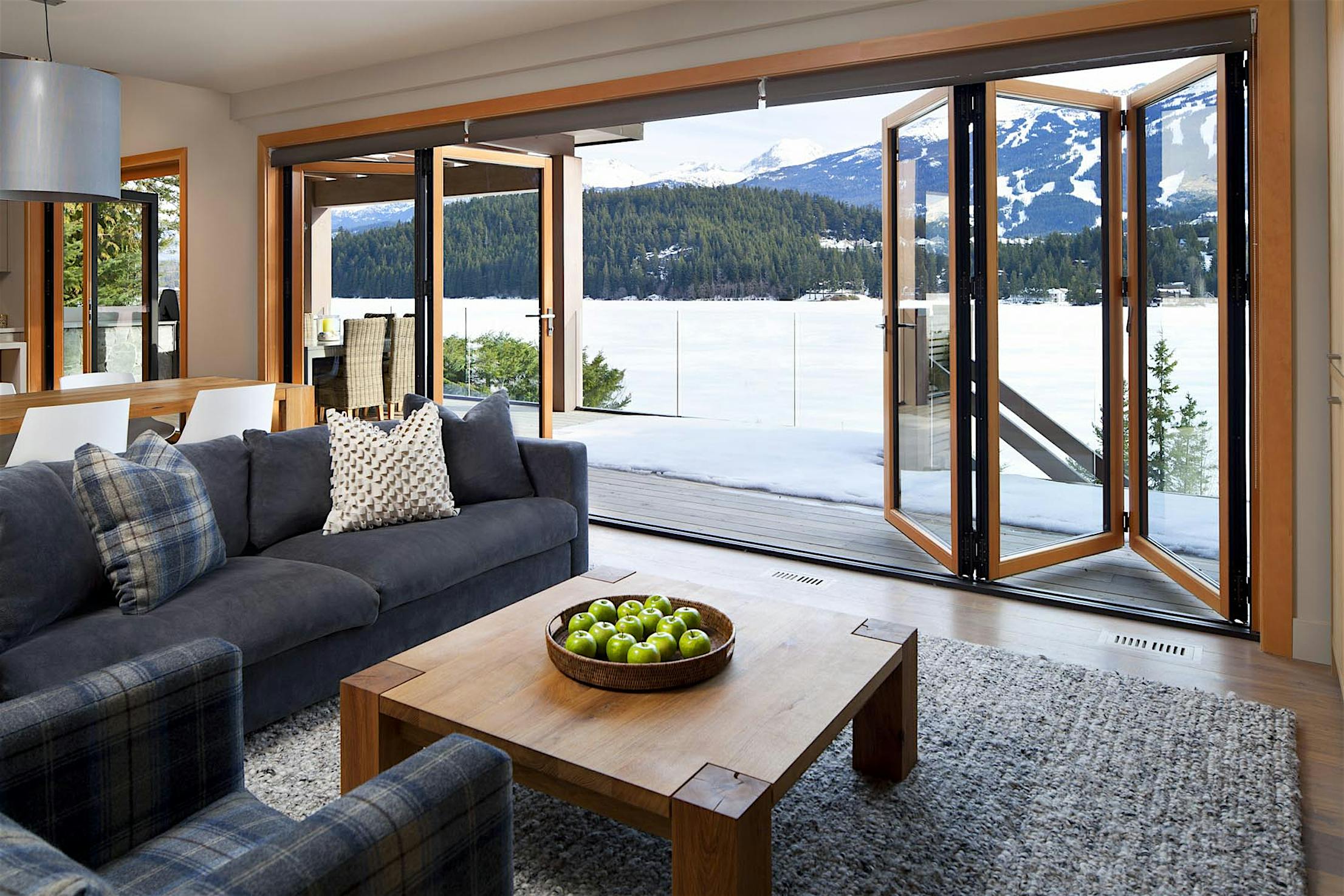 Retractable patio doors in Whistler, BC open to snowy mountain and lake views, offering high‑weather performance
