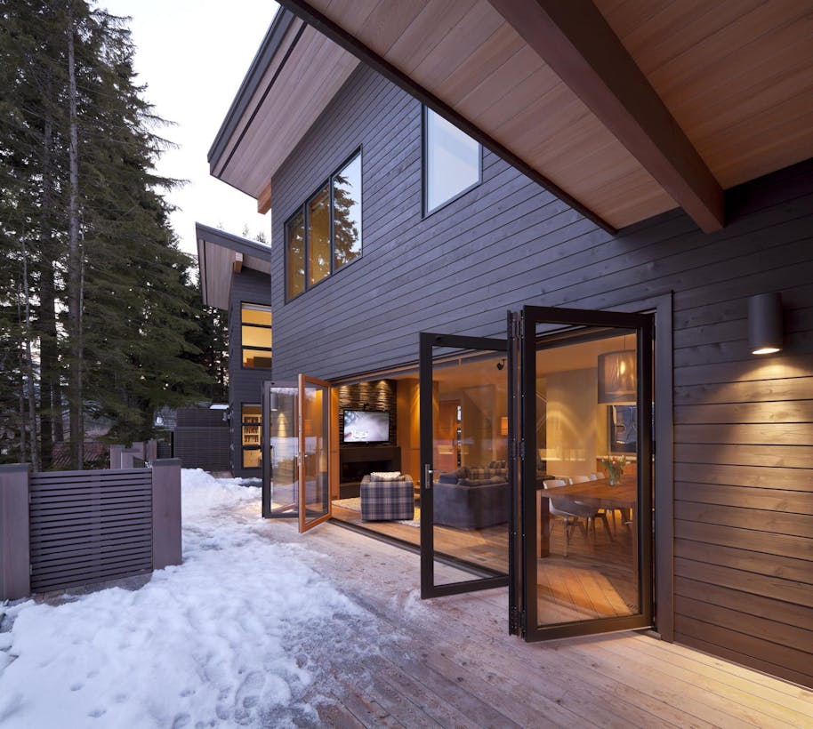A house in the woods with a wooden deck and aluminum clad folding doors