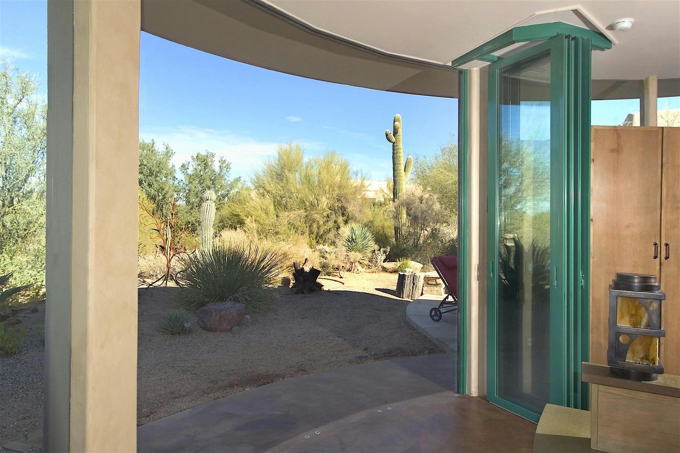High-performance bifold glass doors open to a desert patio with cactus and clear sky, blending indoor and outdoor spaces