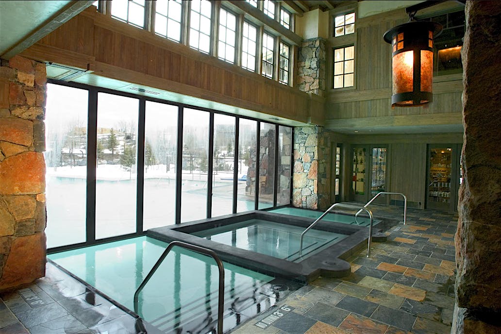 Promontory Club West Jordan, UT | Indoor pool and hot tub with stone flooring and large windows offering snowy views, built for all-season performance and weather protection.