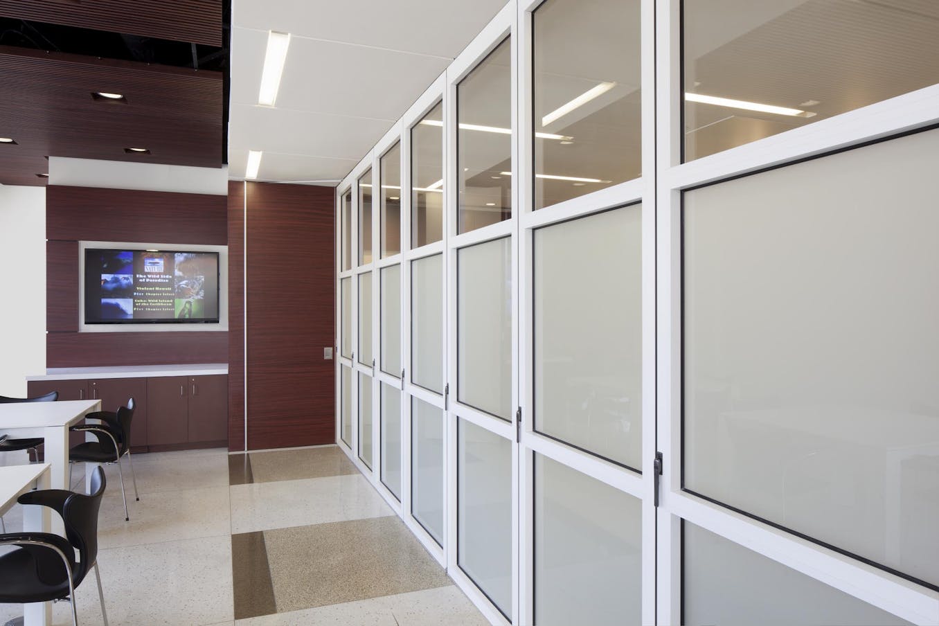A conference room with white glass walls and a waiting room