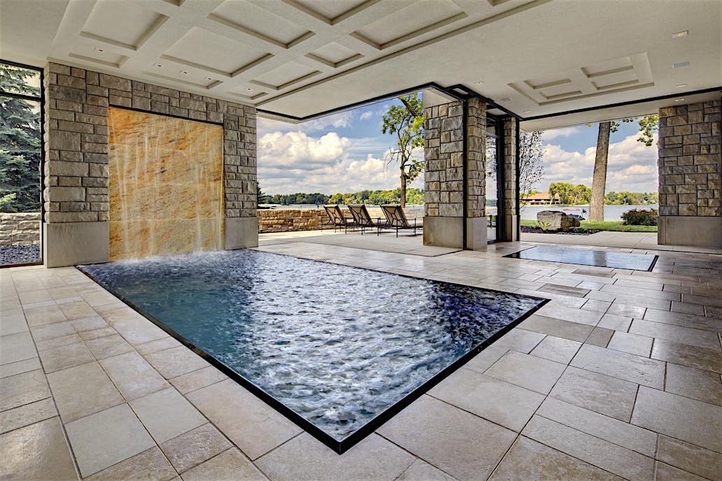 Modern indoor pool with stacking glass doors and stone wall