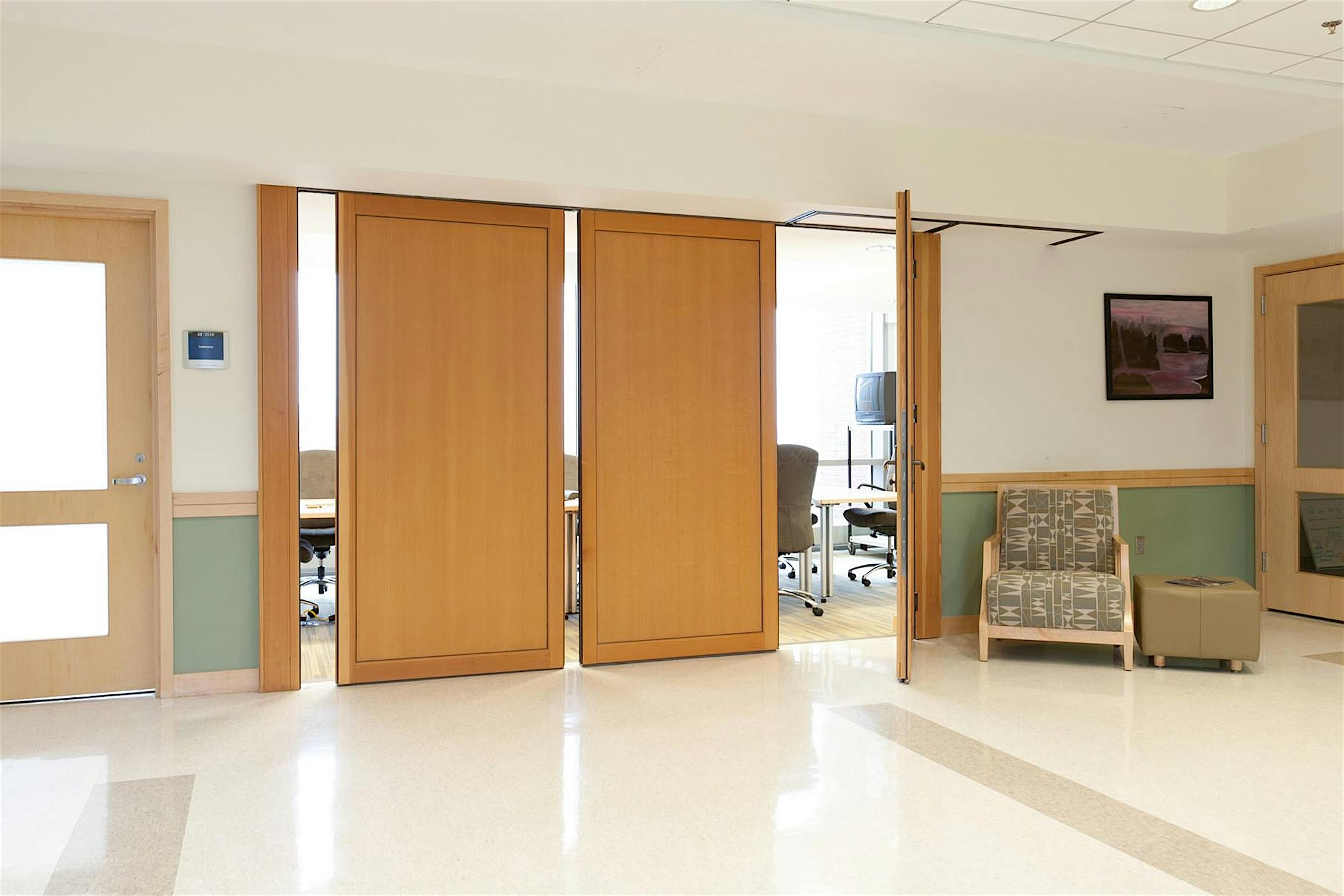 Bright lab hallway with wood-paneled sliding doors leading to a conference room.