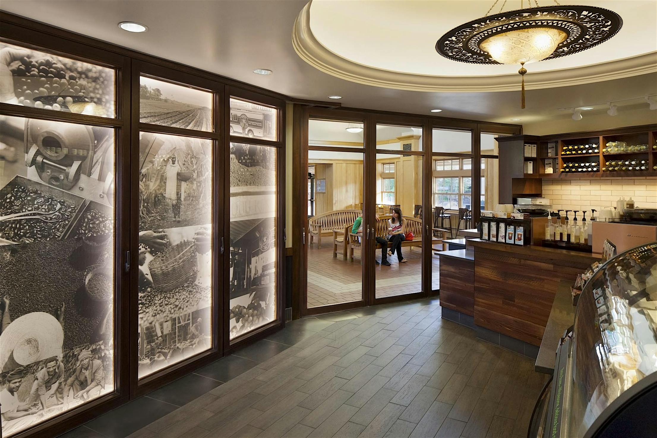 Modern Starbucks interior with wood-framed glass doors opening to a seating area with benches, showcasing an inviting retail space.