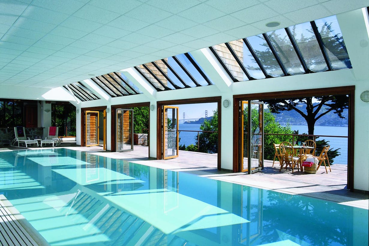 A swimming pool with wood framed folding doors overlooking to the ocean