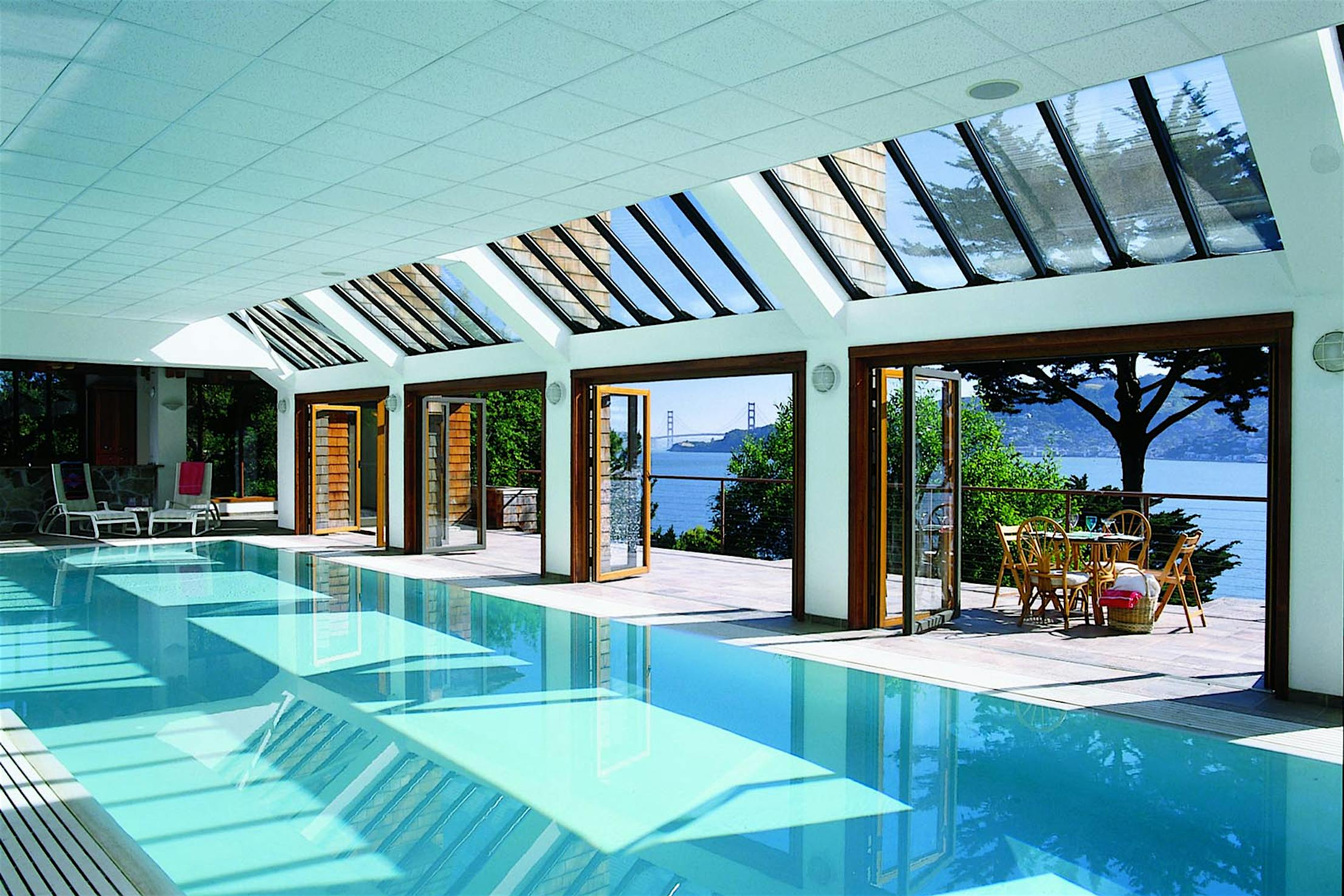 A swimming pool with wood framed folding doors overlooking to the ocean
