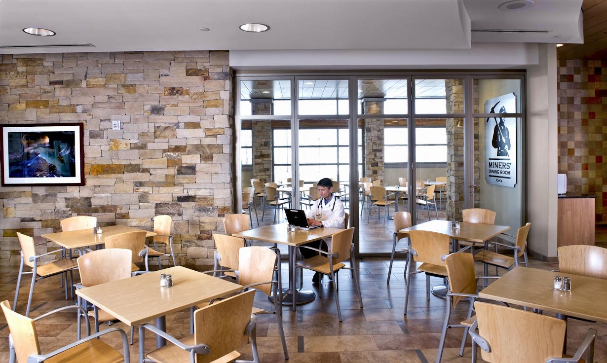 Hospital cafeteria with a person sitting at a table - Aluminum folding glass walls