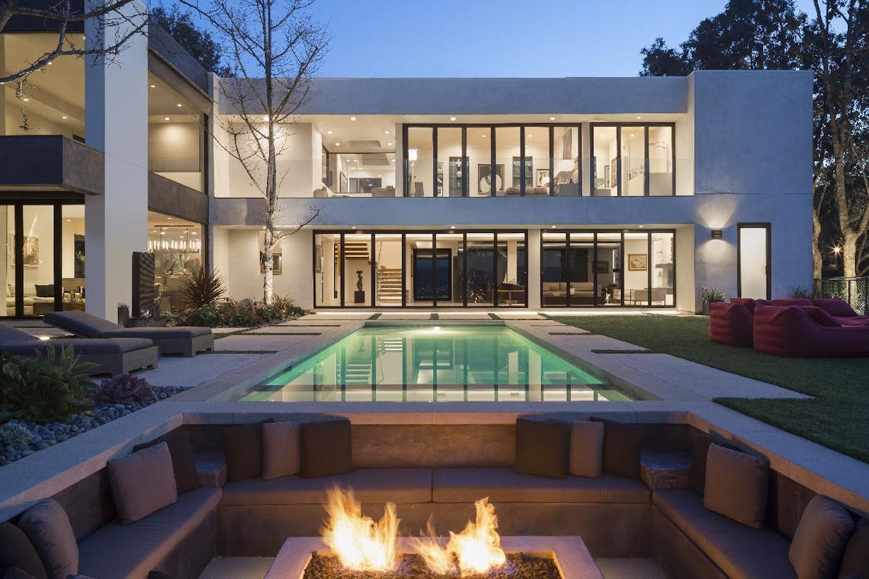A modern home with glass walls rigorously tested for forced entry and a fire pit in the backyard