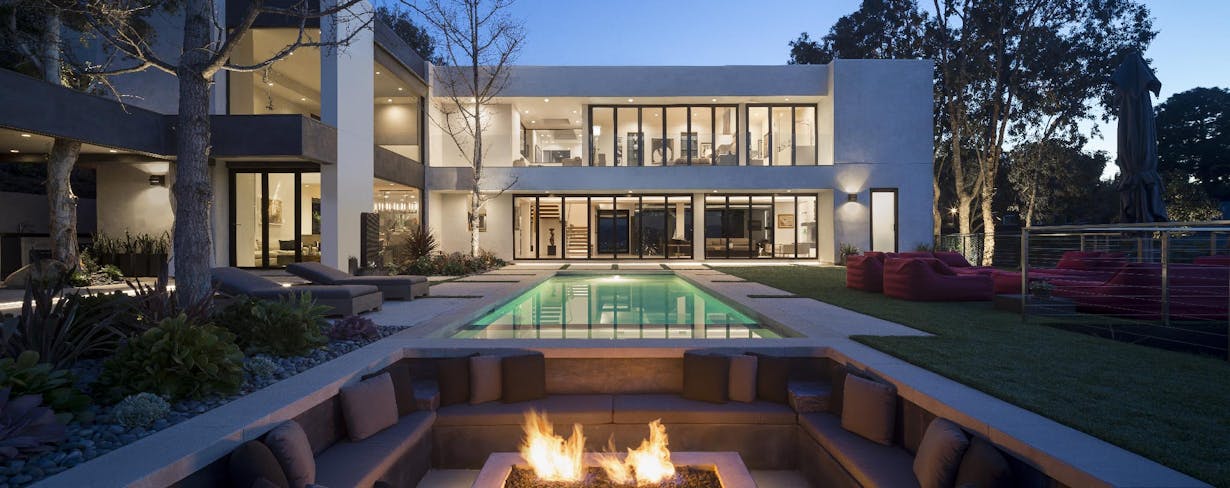 A modern home with glass walls rigorously tested for forced entry and a fire pit in the backyard